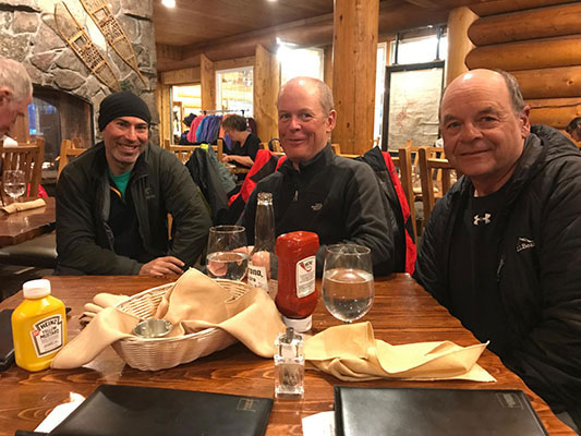 Evan Gilles and Larry around a table in a lodge